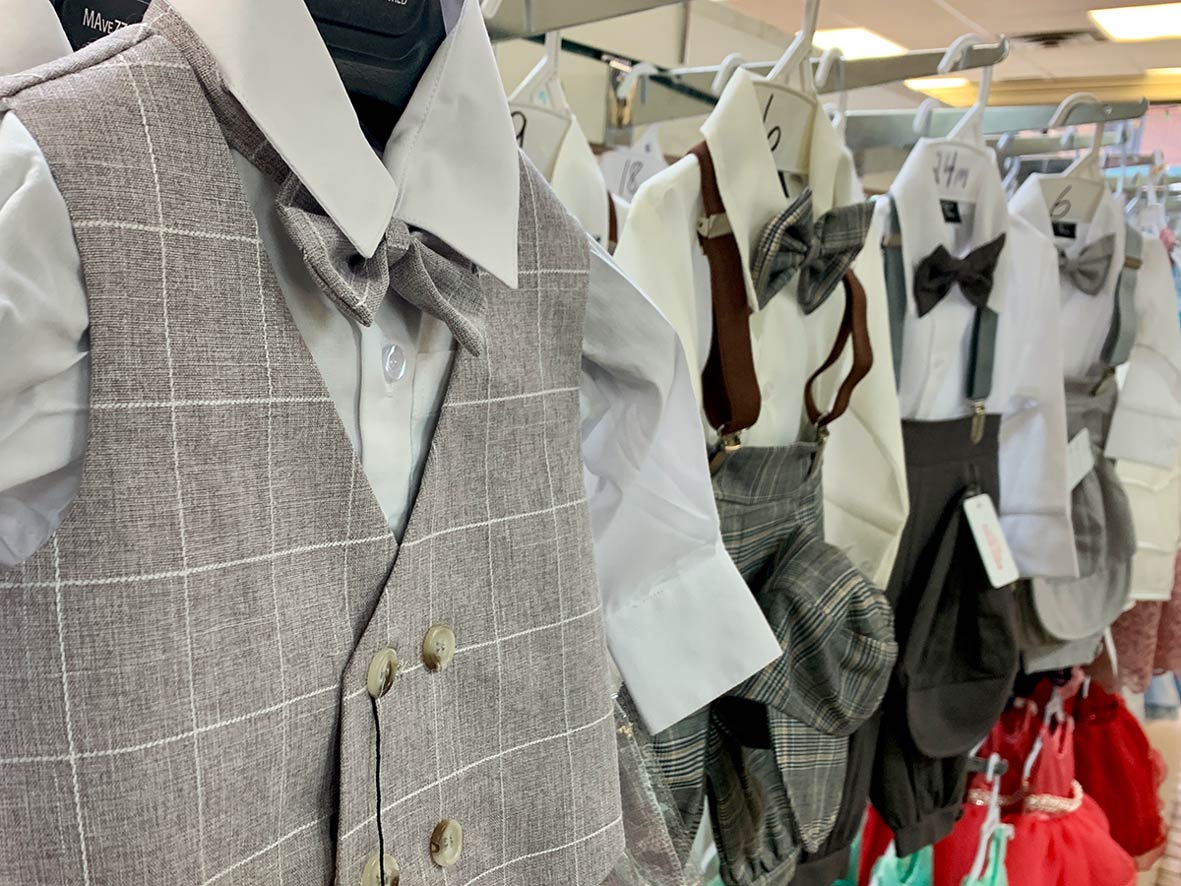 Tiny button-down shirts with matching pants, vest and bow ties hang in aisles